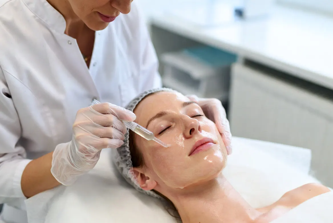 Clinician applying a chemical peel solution to a patient in a treatment room
